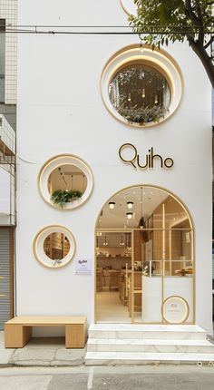 the outside of a store with round windows and circular mirrors on the front wall, along with steps leading up to it