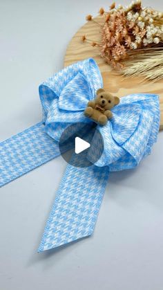 a teddy bear on a blue and white checkered ribbon with a wooden cutting board in the background