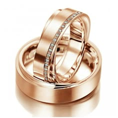 two gold wedding rings with diamonds on each one and the other in their center, sitting next to each other