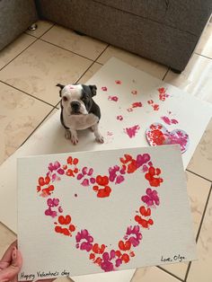 a small dog standing next to a card with hearts drawn on it