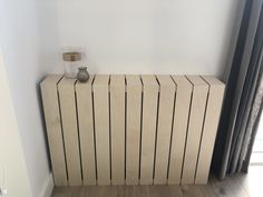 a radiator in the corner of a room with a glass vase on top