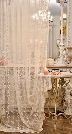 the curtains are hanging in front of the table with candles on it and an ornate mirror behind them