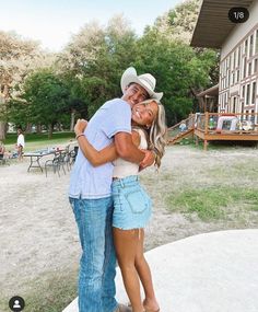 two people hugging each other in front of a building