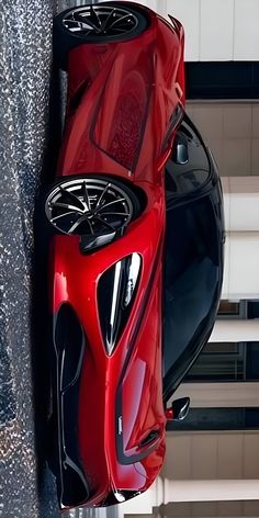 a red sports car is parked next to a wall in an office building, looking down on it's roof