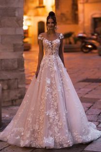 a woman in a wedding dress is standing on the street at night with her hands behind her back