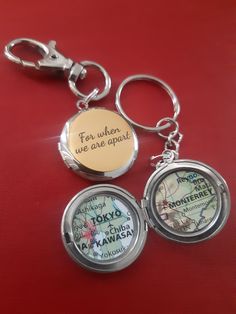 three different key chains that are on top of a red surface, one has a map and the other has a handwritten message