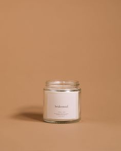 a candle sitting on top of a table next to a brown wall with a white label