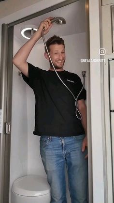 a man standing in the doorway of a bathroom with his headphones hooked up to his hair