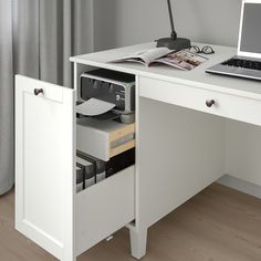 an open drawer underneath a desk with a laptop and printer on it in front of a window