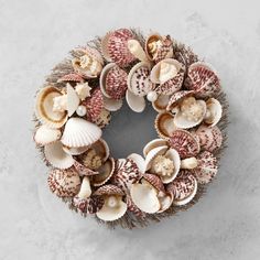 a wreath made out of seashells on top of a white surface with a gray background