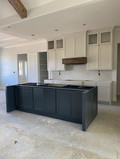 an empty kitchen with white cabinets and black counter tops in the middle of the room