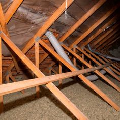 the inside of an attic with exposed pipes and wood floor joisting in it