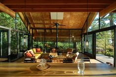 a living room filled with furniture next to a wooden floor covered in glass walls and windows