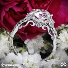 a close up of a ring with flowers in the foreground and a red rose in the background