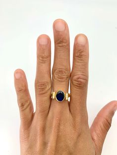 a woman's hand with a ring on it and a blue stone in the middle