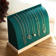 a green display case with gold necklaces and earrings on it's sides, sitting on a wooden table