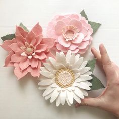 someone is holding three paper flowers in their hand