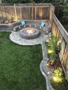 an outdoor fire pit in the middle of a yard with grass and lights around it