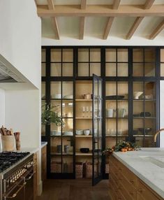 a kitchen with wooden cabinets and white counter tops, along with an open glass door leading to the dining room