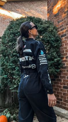 a woman standing in front of a brick wall wearing a black track suit with detroit on it