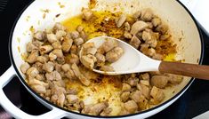 the food is being cooked in the pan on the stove top with a wooden spoon