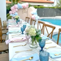 a long table with blue and white plates, silverware and flowers in vases