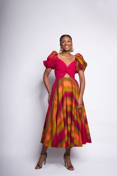 A twisted bodice accent with cutout detailing at a fixed waist seam contrasts with signature puff sleeves and a cascading rainbow midi length skirt. Raw edging and and a zipper finishing. Luxury Spring Puff Sleeve Dress With Ruched Bodice, Luxury Puff Sleeve Dress With Ruched Bodice For Spring, Nigerian Puff Sleeve Dress, Puff Sleeve Trapeze Dress, Fitted Multicolor Puff Sleeve Midi Dress, Multicolor Fitted Midi Puff Sleeve Dress, Multicolor Fitted Puff Sleeve Dress, Fitted Multicolor Midi Dress With Gathered Sleeves, Multicolor Midi Dress With Gathered Sleeves