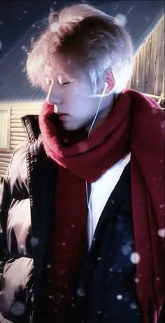 a boy wearing ear buds and a red scarf