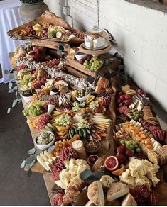 an assortment of cheeses, fruits and meats on a table in a room