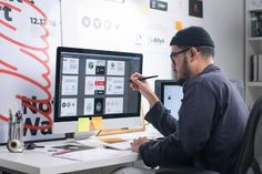 a man sitting at a desk with a computer and pen in front of his face