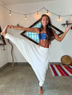 a woman standing in a room with her arms stretched out and wearing a white skirt