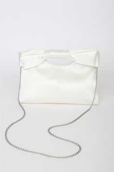 Complete your big day look with the Lulus Total Romantic White Satin Bow Clutch! Sleek woven satin shapes darling clutch that has a cutout handle at the top and a decorative bow at the front. Magnetic closure opens to a lined interior with a single sidewall pocket. Detachable silver chain strap. Fully lined. Bag measures 10. 5" wide, 7. 5" tall, and 1. 75" deep (relaxed). Detachable 46" strap. Strap has a drop of 22â€. Shell: 100% Polyester. Lining: 100% Polyester. Imported. Lulus | Total Roman Elegant Bags With Decorative Bow, Elegant Wedding Bags With Bow Detail, Elegant Wedding Bags With Bow, Elegant Clutch Bag With Bow, Elegant Bags With Bow For Events, Chic Wedding Bags With Bow Detail, Chic Wedding Bag With Bow, Chic Wedding Bags With Bow, Chic Bow Evening Bag For Party