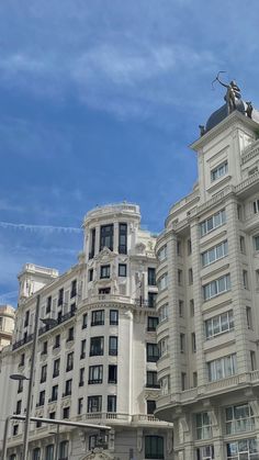 a large white building with many windows and statues on the top, in front of a blue sky