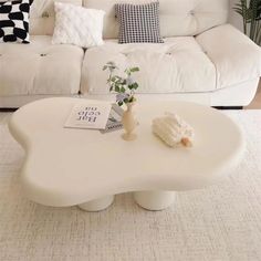 a white coffee table sitting in front of a couch with pillows on top of it