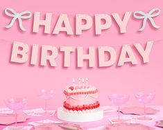 a birthday cake sitting on top of a table next to pink plates and wine glasses