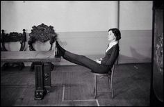 a black and white photo of a woman sitting in a chair with her leg up