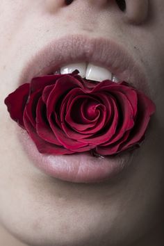 a close up of a woman's mouth with a flower in the middle of her tongue