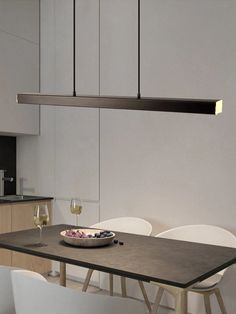 a dining table with two chairs and a bowl of fruit on it next to the kitchen counter