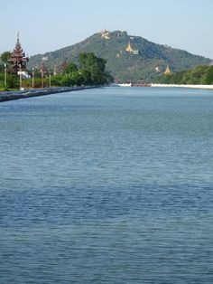 a large body of water with mountains in the background and trees on both sides,