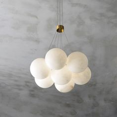 a chandelier hanging from the ceiling in a room with concrete walls and flooring