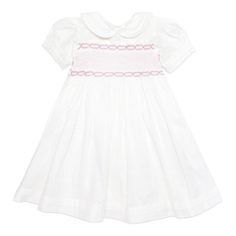 This gorgeous traditional white cotton dress is a perfect addition to your child's wardrobe.  It can be dressed up or down.  Ideal for any occasion with a stunning deep hand smocked central panel in pink adding a beautiful classic feel.  Made with love it features a peter pan collar, a gorgeous puff sleeve with pleated turn back cuffs finished off with buttons down the back.  100% Cotton Fully lined 100% Cotton Machine wash at 30 degrees Wash with similar colours Fitted White Smocked Cotton Dress, White Fitted Smocked Cotton Dress, White Fitted Cotton Smocked Dress, White Fitted Smock Dress, Pink Cotton Smocked Dress With Short Sleeves, Pink Smocked Dress With Smocked Cuffs For Daywear, Pink Cotton Dress With Smocked Bodice, Classic Daywear Dress With Smocked Bodice, Pink Short-sleeved Dress With Smocked Cuffs