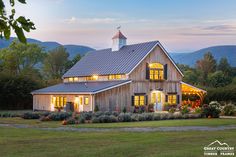 a large wooden house with windows lit up at night in front of trees and mountains