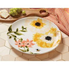 a white plate with yellow and pink flowers on it next to a wooden cutting board