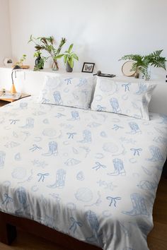 a bed with blue and white sheets in a bedroom next to a potted plant