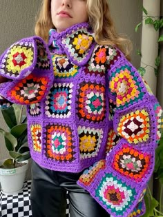 a woman wearing a purple crocheted jacket with colorful granny grannys on it