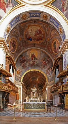 the inside of a church with paintings on the walls and ceiling, along with pews