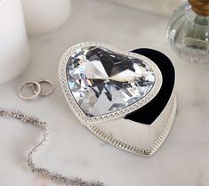 a heart shaped box sitting on top of a table next to a necklace and ring