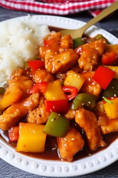 a white plate topped with chicken and veggies next to rice on a table