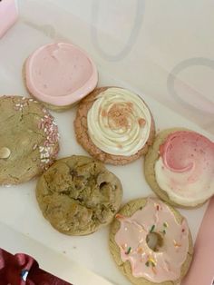 a box filled with assorted cookies and frosted doughnuts on top of each other