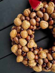 a wreath made out of nuts on top of a wooden table next to a red bow